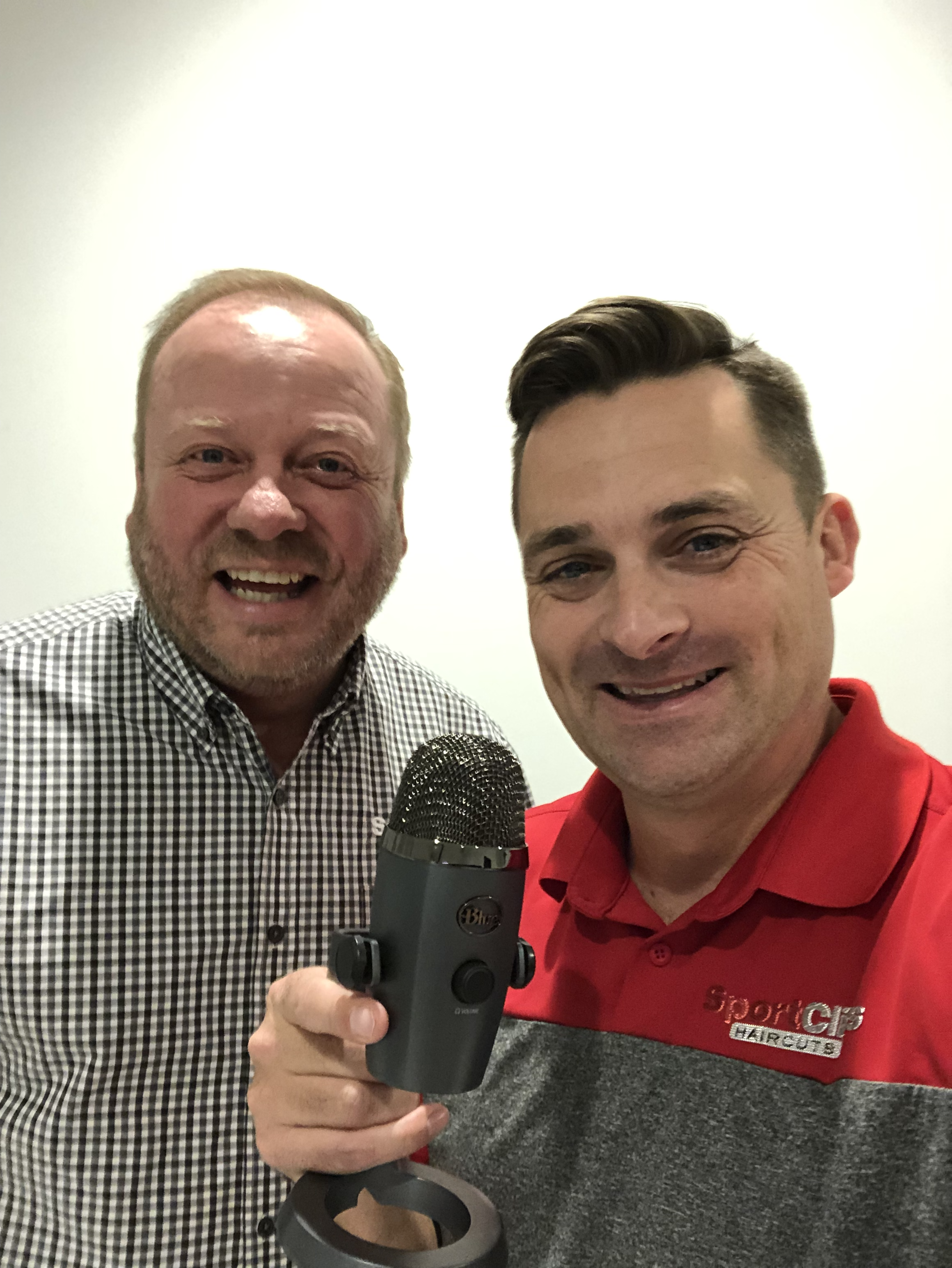Duke Sorensen and Chad Jordan holding a microphone for their podcast